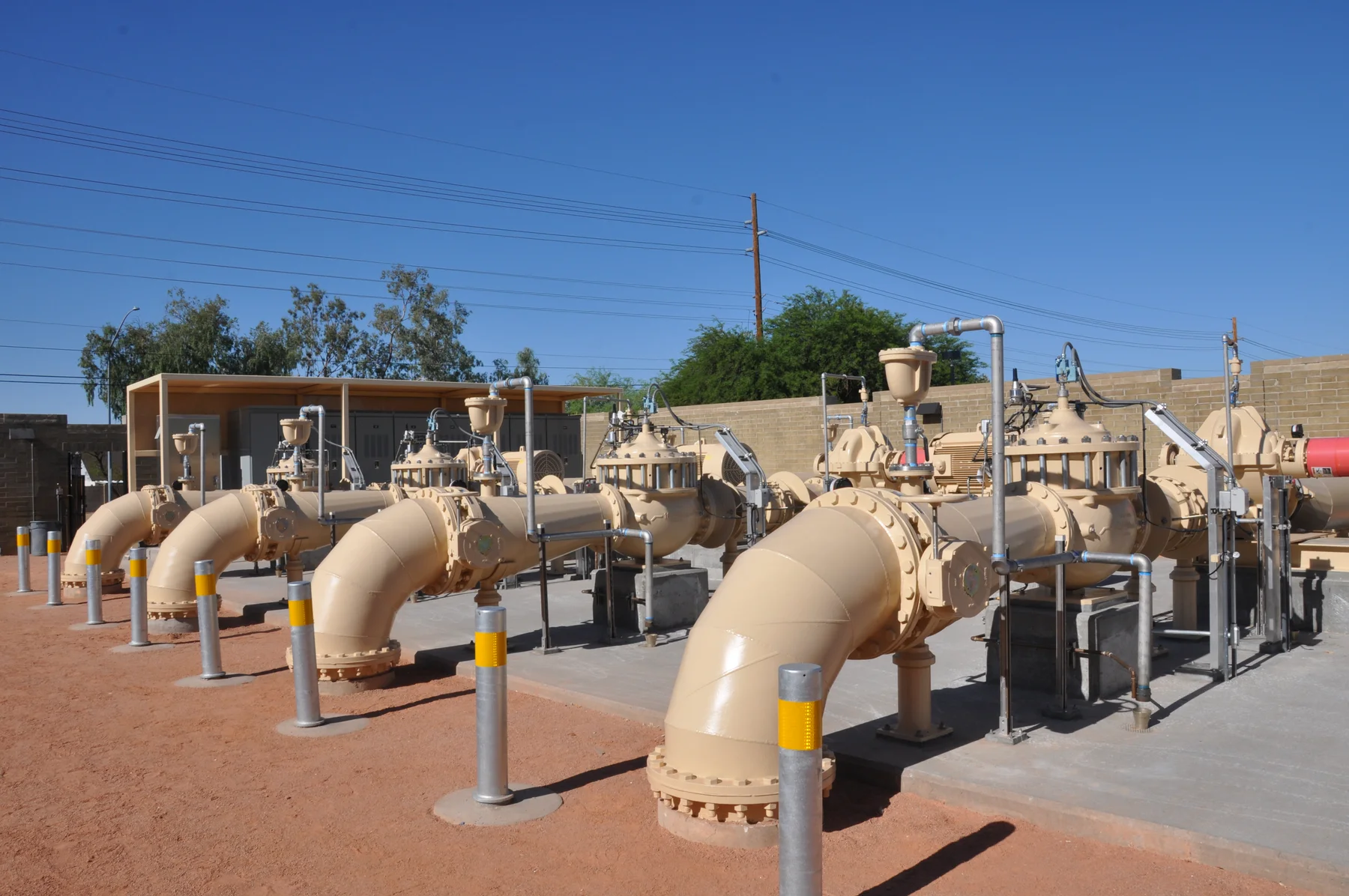 Water main valve manifold with bollards and piping at a pump station site
