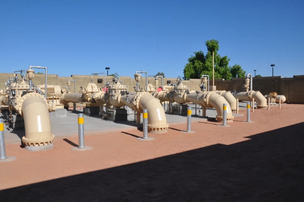Row of large water main valves and bollards at a pump station facility