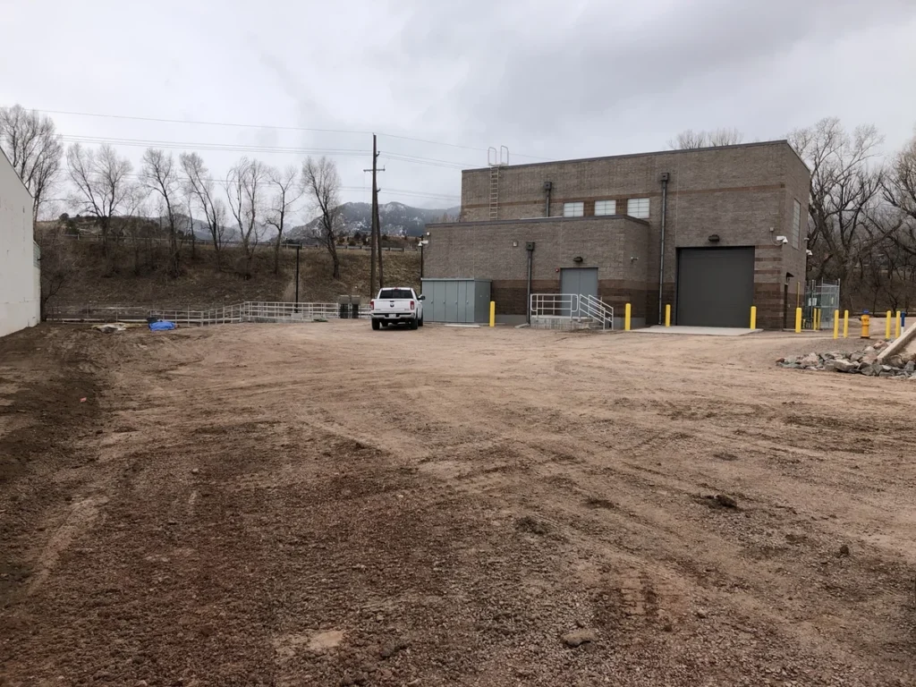 Completed pump station building exterior with mountain backdrop and gravel yard