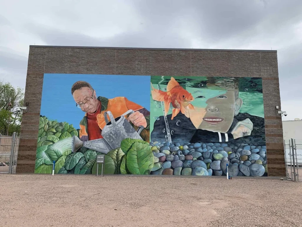 Pump station exterior wall with colorful mural depicting a gardener and child with aquatic theme