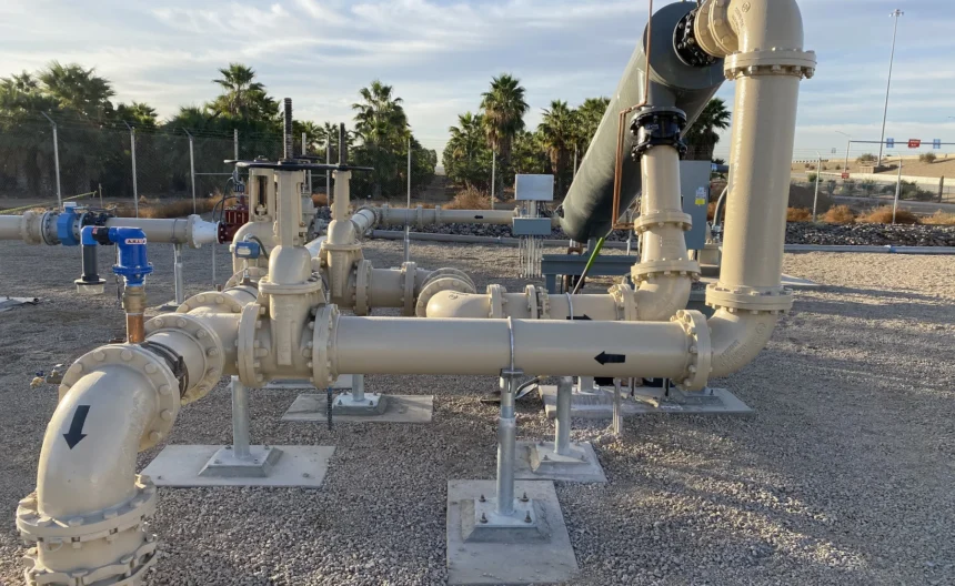 Well pump station piping and valves with palm trees in the background