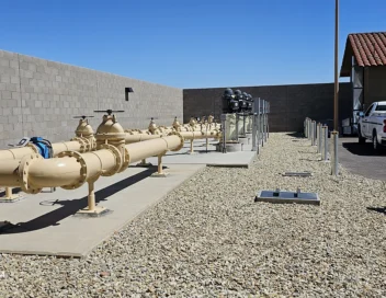 Row of water main valves and piping along a concrete pad at a desert utility site