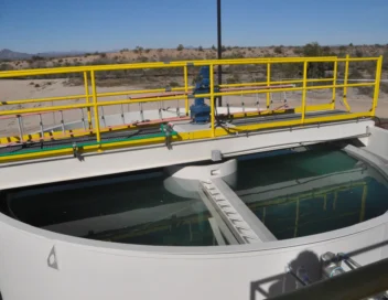 Water treatment clarifier tank with yellow safety railings in a desert setting