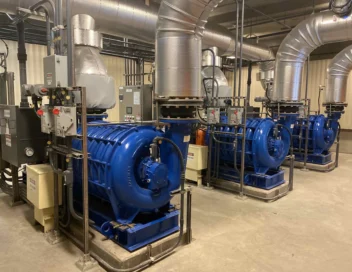 Blue centrifugal water pumps and motors inside a pump station mechanical room