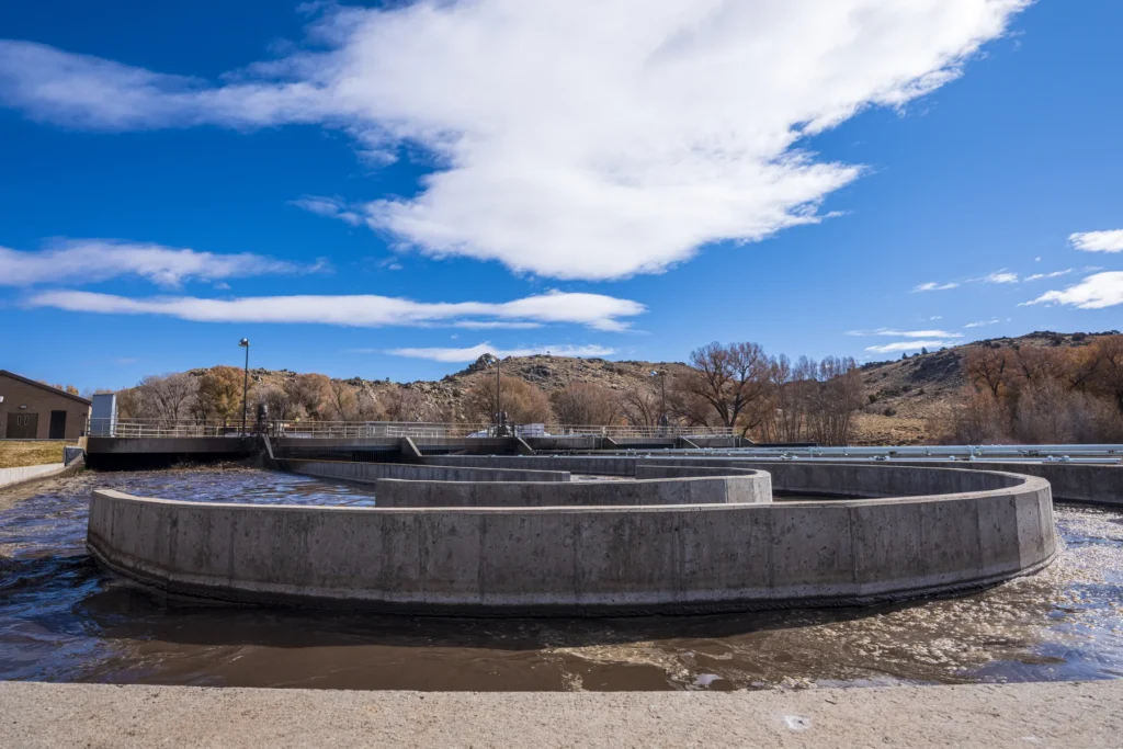 Concrete oxidation basins at Gunnison wastewater treatment plant under a clear blue sky with rolling hills