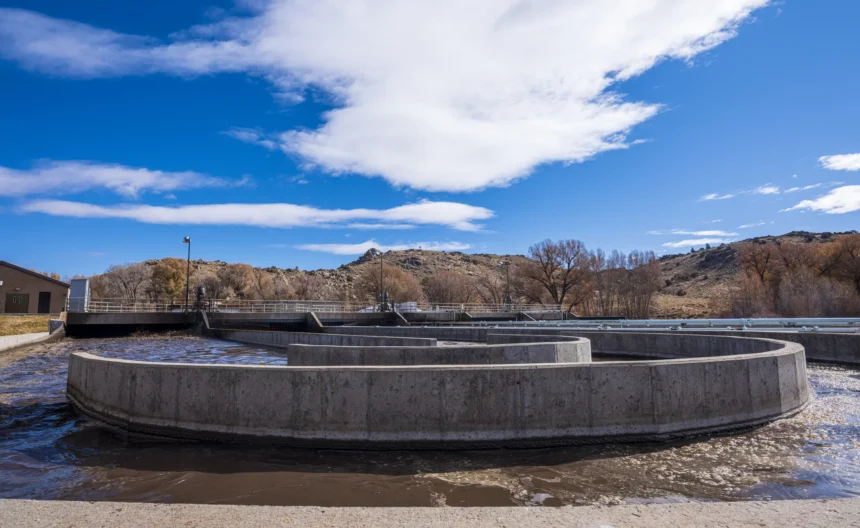 Concrete oxidation basins at Gunnison wastewater treatment plant under a clear blue sky with rolling hills