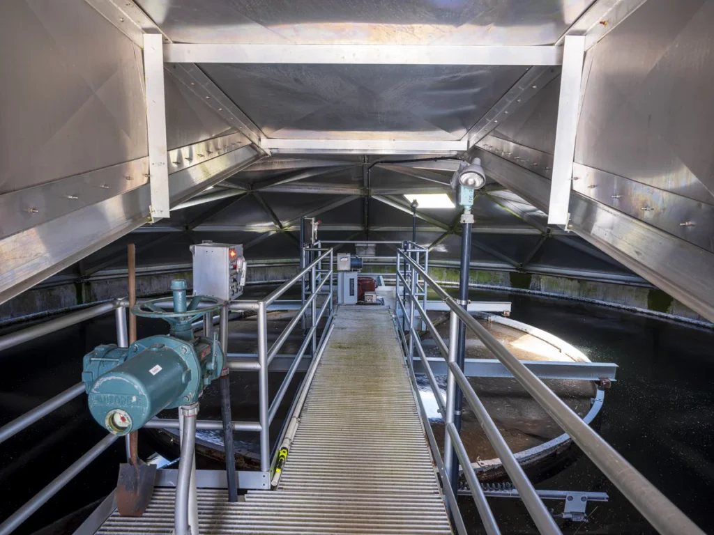 Interior walkway of covered pumping station showing aluminum dome structure and treatment equipment