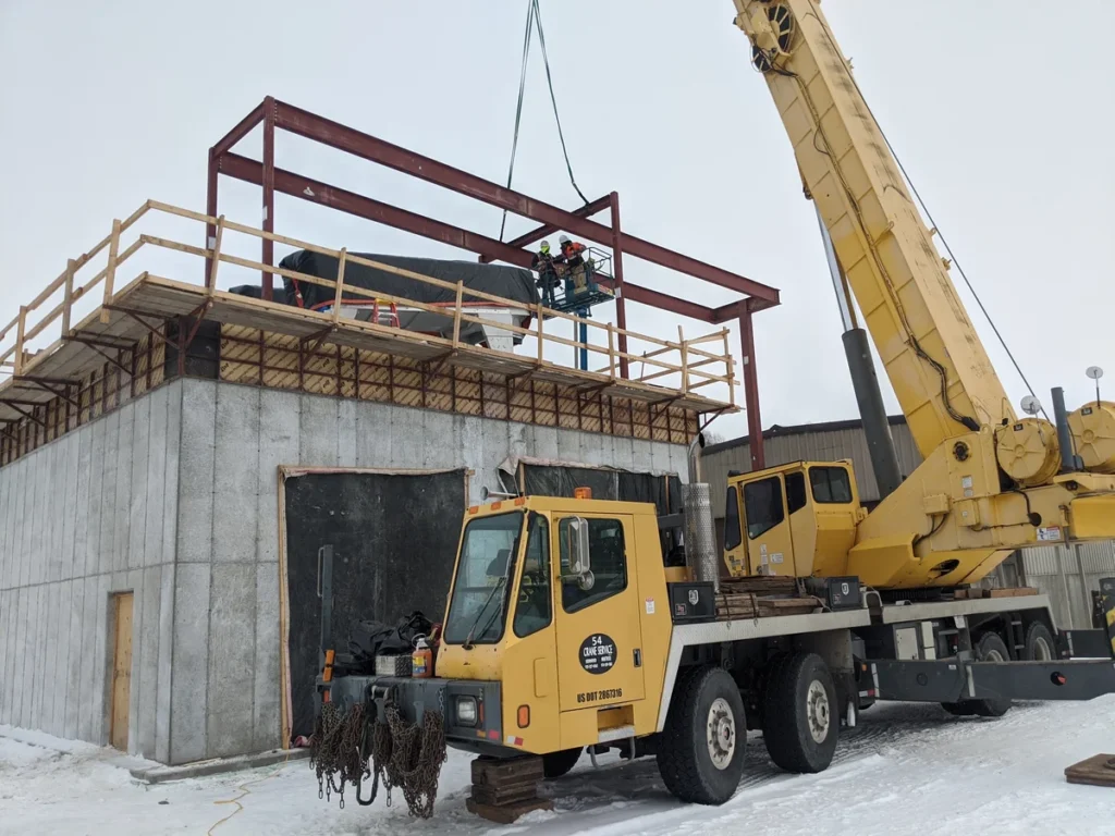 Winter construction scene with crane setting steel beams on a concrete structure at Gunnison WWTP
