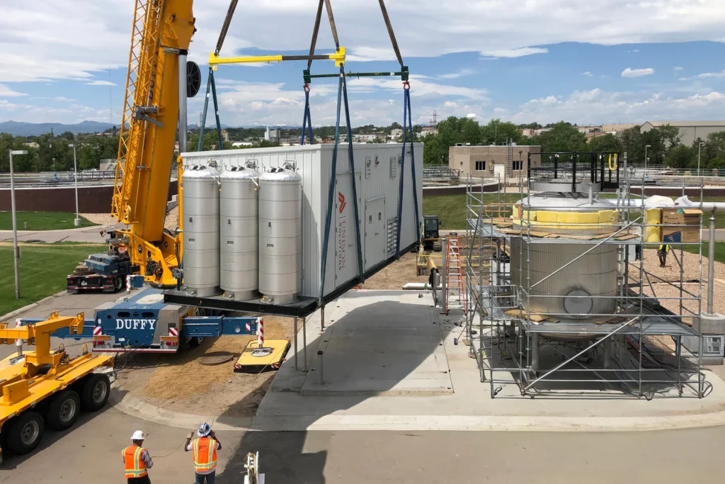 Crane lifting a large modular pipeline injection unit into place at Littleton Englewood WWTP