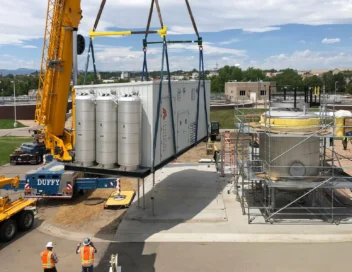 Crane lifting a large modular pipeline injection unit into place at Littleton Englewood WWTP