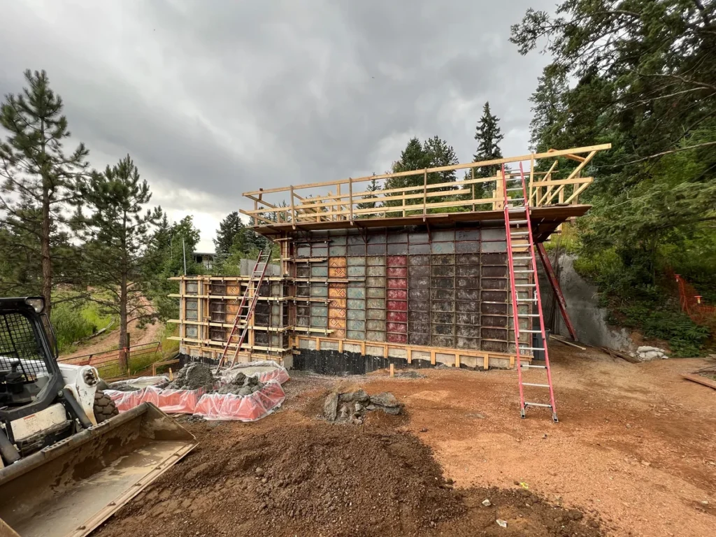 Concrete wall formwork and framing during booster pump station construction with skid steer on site