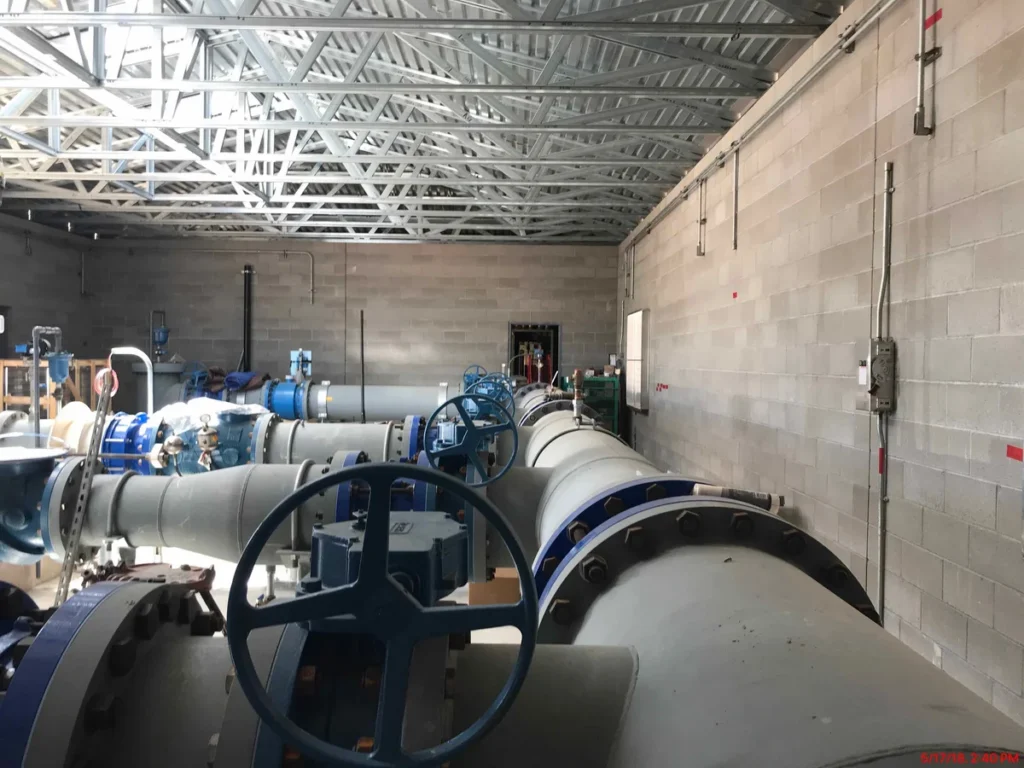 Large-diameter pipeline with blue butterfly valves and hand wheel operators inside pump building