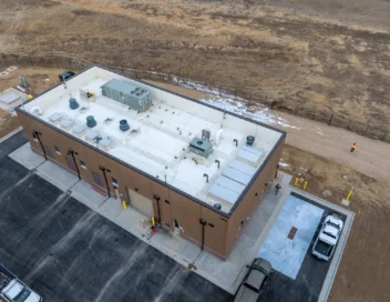 Aerial drone view of completed WISE Pump Station building with parking area in open landscape
